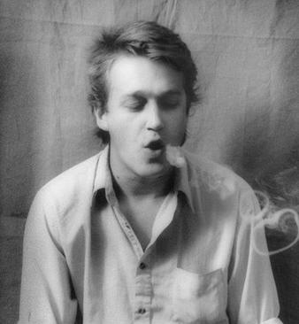 A black-and-white photo of a man blowing smoke rings